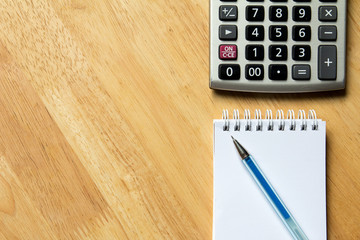 Calculator, pen, blank note book on wood table