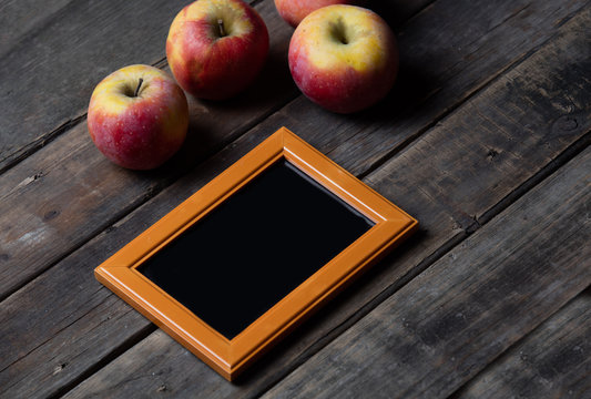 beautiful empty frame and fresh apples lying on the wonderful wooden brown background