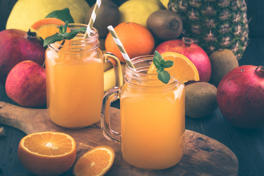 Glass jars of citrus drink on various fruits background. Toned
