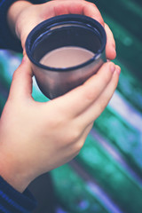 A cup with a hot drink in the children's hands   in the street