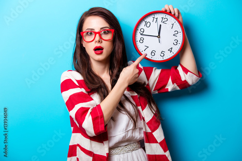 Beautiful Surprised Young Woman With Clock Standing In Front Of