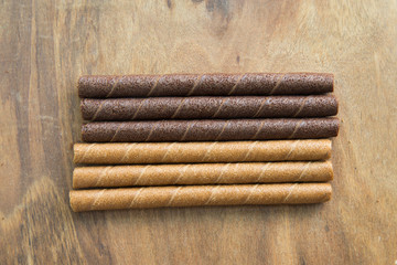 wafer rolls with chocolate on wooden table.