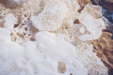Spring background. Melting ice on beach on a sunny spring day. Macro shot.