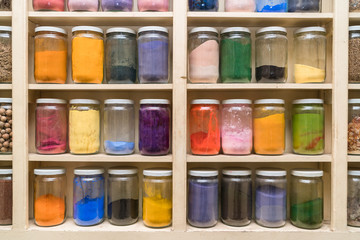 Glass bottles with colorful spices on the shelfs
