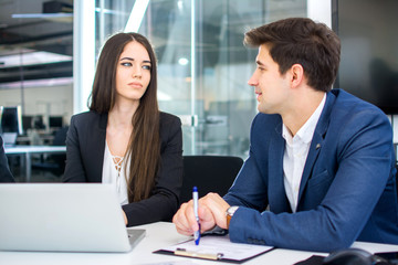 Young businesswoman communicating with male colleague in the office.