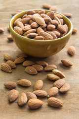 Almonds in bowl on wooden background , focus on almonds in bowl.