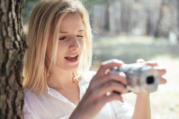 Blonde girl holding a retro camera,  young woman is a photographer with vintage camera, outdoor and sunlight, Portrait, copy space.