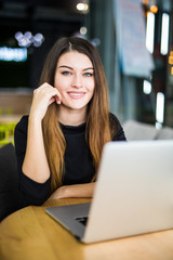 Close up portrait of a beautiful young woman smiling and looking at camera with laptop