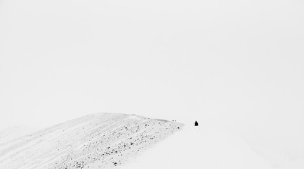 Tiny human figure on the edge of a volcano crater - breathtaking Iceland in winter - amazing landscapes, storms and blizzards - photographers paradise