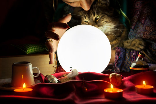 Glowing crystal ball with gypsy fortune teller who holds a cat