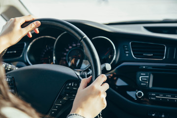 Naklejka premium Female hand on the driving wheels. Driving a modern car steering wheel and hand close-up.