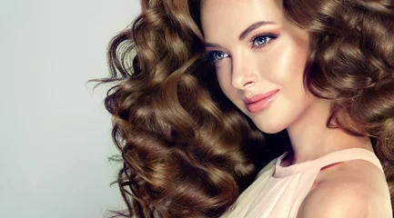 Photo sur Plexiglas Salon de coiffure Belle fille modèle avec une longue coiffure ondulée. Femme brune aux cheveux bouclés