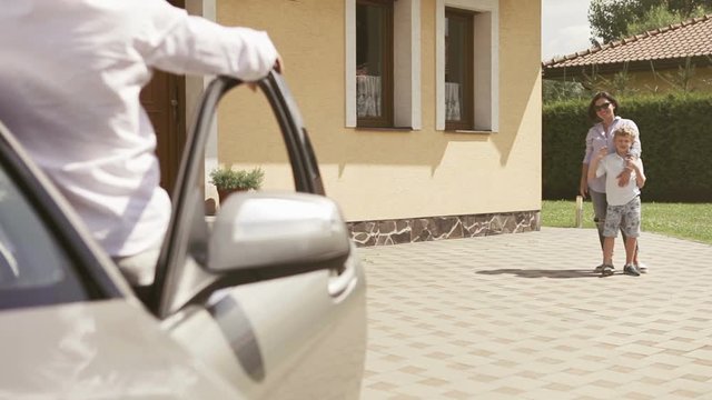 Father is about to leave on a business trip: says goodbye to the family at the car