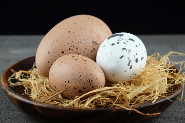 Easter eggs on wooden plate with hay.