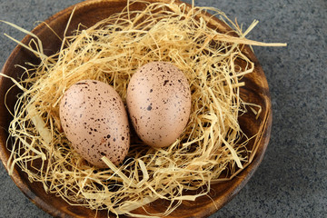 Naklejka na ściany i meble Two quail easter eggs on wooden plate with hay.
