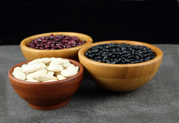 Various kinds of beans in a wooden bowl.
