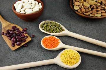 Various kinds of beans and lentils in wooden bowls and spoons.