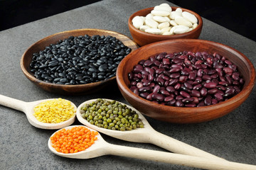 Various kinds of beans and lentils in a wooden bowl.