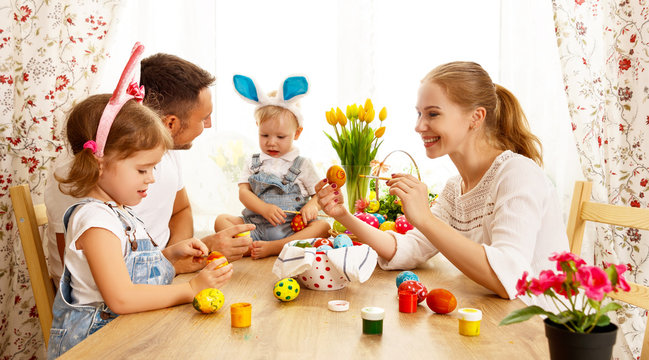 Happy easter! family mother, father and children paint  eggs for holiday.