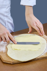 Chef smears butter on the dough for the preparation of baking cooking