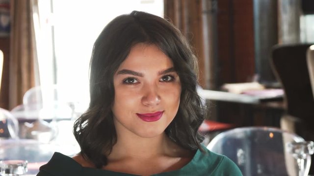 portrait of happy brunet young woman look and smile at camera while sitting on dating in cafe