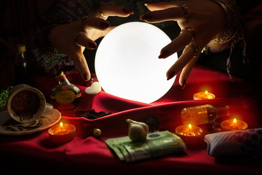 Hands from fortune teller above crystal ball
