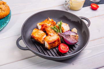 Close up bbq chicken breast with vegetables in a frying pan on the white wooden background with details. Selective focus