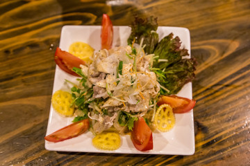 Colorful pork salad with green lettuce, onion and tomato and sesame dressing.