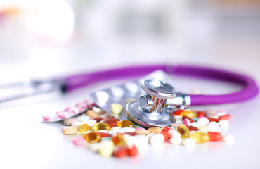 Stethoscope and some pills - isolated on a white background