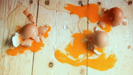 Zelfklevend Fotobehang three broken eggs on wooden flloor © wernerimages