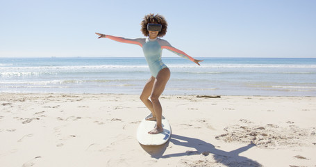 Female wearing virtual reality glasses standing on surfboard on sea background, Tarifa beach....