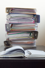Five folders with documents stacked in a pile on the table