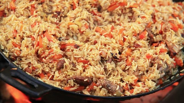 Colorful plov(Middle East dish from rice and meat)is being prepared on open fire