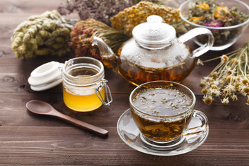 medicinal tea in glass cup with dried herb in bowl
