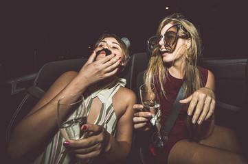Party girls celebrate in Hollywood drinking champagne on a covertible car - obrazy, fototapety, plakaty