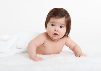 Adorably baby lie on towel in bed, white background. Happy childhood and healthcare concept