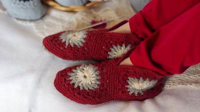 Female feet in knitted slippers are moving to the music. Close up