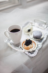 A cup of coffee a sandwich of black caviar on a silver tray. Breakfast millionaire