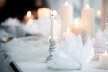White burning candle in a candlestick on a background of candles.