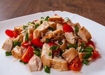 chicken and rice salad with fresh tomatoes in a plate on wooden table