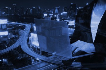 double exposure of smart businessman using laptop with blurred city night background.