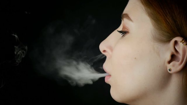 Young Beautiful Woman Smoking Electronic Cigarette On Black Background
