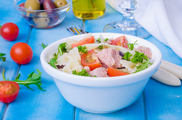 Pasta salad with tuna, olives, cherry tomatoes and arugula
