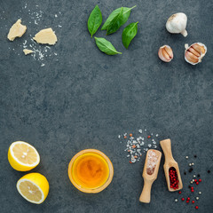 The ingredients for homemade pesto sauce basil, parmesan cheese ,garlic, olive oil , lemon ,pine nut ,pepper corn and himalayan salt on dark stone background with flat lay and copy space.