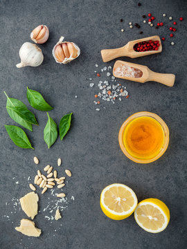The ingredients for homemade pesto sauce basil, parmesan cheese ,garlic, olive oil , lemon ,pine nut ,pepper corn and himalayan salt on dark stone background with flat lay and copy space.