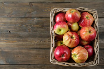 basket with red ripe apples on a brown wooden table