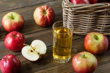 A glass of juice on a background of red ripe apples