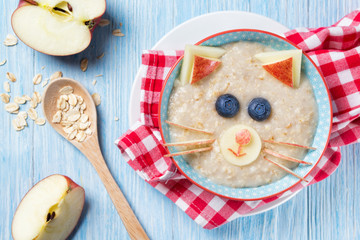 Funny oat porridge with cat, kitten face made of fruit and berries, food for kids idea, top view