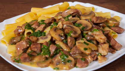 rigatoni pasta with meat and mushroom sauce in a plate on wooden table