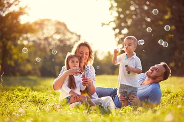 Fotobehang Family with children blow soap bubbles outdoor © luckybusiness